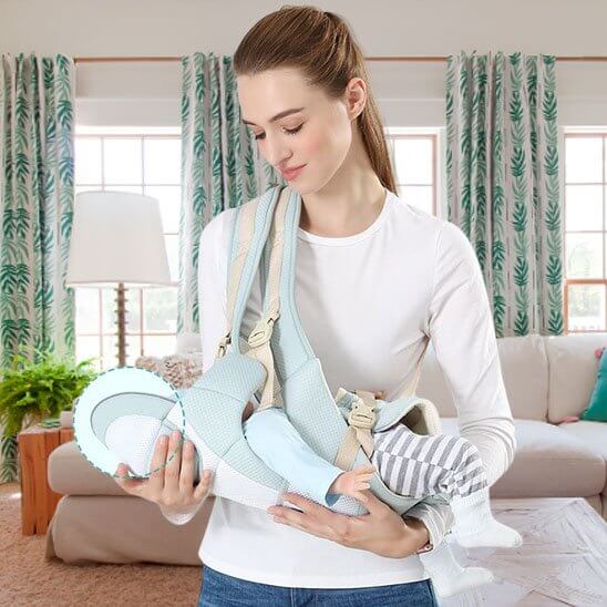 Porte bébé comfort +, maman utilisant un porte bébé ergonomique à la maison avec un bébé dans ses bras.